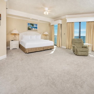 Spacious master suite bedroom, featuring a king bed, cozy seating, and beachfront balcony access