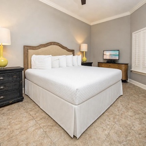 This cozy guest bedroom features a plush king bed, a vibrant yellow lamp, and a TV for relaxing evenings