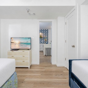 Cozy guest bedroom featuring a TV, stylish decor, and a glimpse of the other accommodations beyond