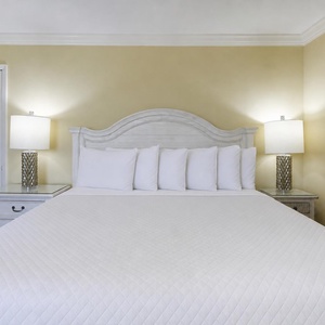 Brightly lit master bedroom featuring a large king bed adorned with plush white pillows and stylish bedside lamps