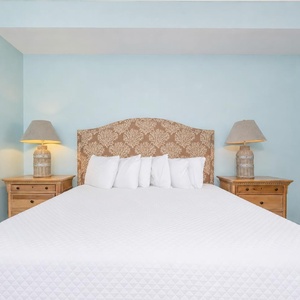 Master bedroom featuring a king bed, elegant lamps, and soothing blue walls for a relaxing getaway