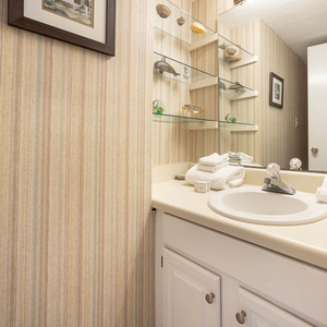 This extra half bath features a clean design with a well-lit vanity, and neatly arranged towels for a refreshing experience