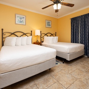 Relax in this cheerful guest room featuring two comfortable queen beds, a cozy lamp, and charming nautical decor