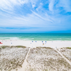 This stunning beachfront view showcases soft white sand and inviting blue waters, perfect for a relaxing getaway