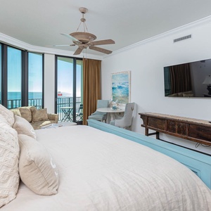 The master suite bedroom features a plush king bed, comfortable seating, and large windows with beautiful views