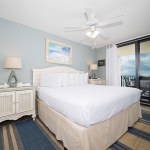 Bright master bedroom featuring a king bed, coastal decor, and access to a balcony with views of the gulf