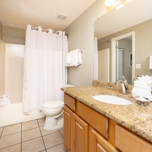 Experience convenience in this guest bathroom featuring a spacious vanity, fresh towels, and a relaxing tub-shower