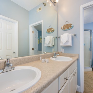 The master bathroom features dual sinks, a spacious tub, and a refreshing shower, all accented by soft blue walls