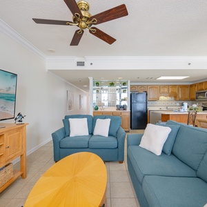 Cozy living space features a turquoise sofa, a dining table with rattan chairs, and a breakfast bar, perfect for beach days