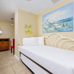Cozy bedroom featuring a charming twin daybed with twin trundle, colorful beach artwork, and a stylish dresser for storage