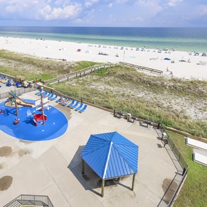 The view showcases a vibrant pool area and pirate ship splash park, surrounded by lounge chairs and just steps from the beach