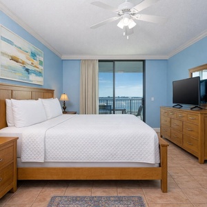 Relaxing master bedroom featuring a king bed, wooden furniture, and a stunning bay view from the balcony