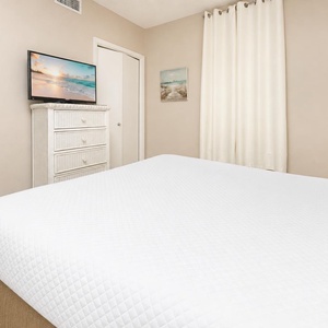 Relax in this inviting guest bedroom featuring a queen bed, a TV, and soft decor that enhances your restful experience
