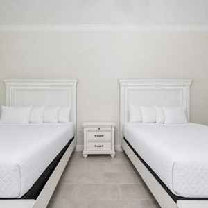 Cozy guest room featuring two queen beds, a nightstand, and a calming color palette for a restful stay