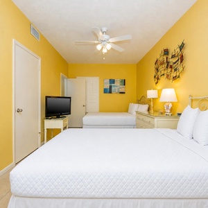Cheerful guest bedroom featuring two queen beds, and vibrant yellow walls for a welcoming atmosphere