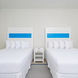 Cheerful guest bedroom featuring two queen beds with blue-striped headboards and a relaxing vibe