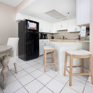 Bright kitchen area featuring white cabinetry, a breakfast bar with stools, coffee station, and a dining area
