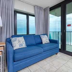 Relax on the blue sofa, enjoying views through large windows that invite in the tranquil atmosphere of the coast