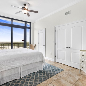 This bedroom features a comfortable king bed, a TV, and large windows offering a beautiful beachfront view