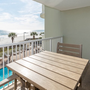 This balcony offers a stunning view with a wooden table and chairs, perfect for relaxing and enjoying the scenery