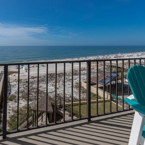 Relax on the balcony with vibrant teal chairs, overlooking the serene beach and inviting turquoise waters