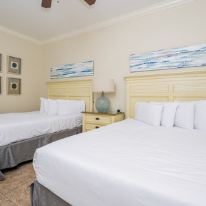 This guest bedroom features two comfortable full beds, soft white linens, and coastal artwork, creating a serene atmosphere