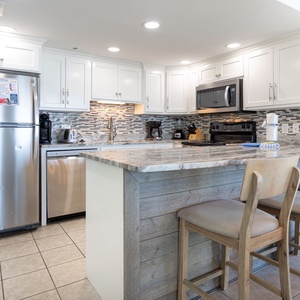 Prepare meals in this sleek kitchen featuring stainless appliances and a spacious bar with seating
