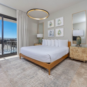 Unwind in this serene master bedroom featuring a plush king bed, stylish decor, and sliding doors to the beachfront patio