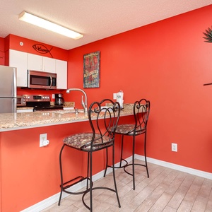 The kitchen features vibrant walls, granite countertops, stainless appliances, and bar seating for a cheerful experience