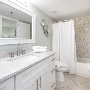 The bathroom features a marbled countertop with modern fixtures, a tub/shower combo, and elegant decorative accents