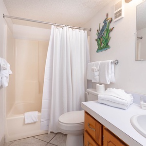 Enjoy a refreshing shower in the master bath surrounded by fresh towels and coastal decor, perfect for your beach retreat