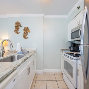 Modern kitchen featuring white and stainless appliances, marble countertops, and charming seahorse decor