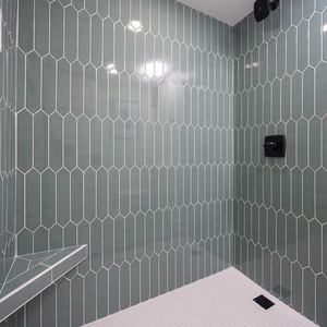 Stylish walk-in shower in the master bath features hexagonal green tiles and a built-in bench for a refreshing experience