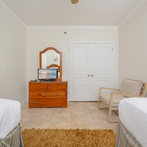Cozy guest bedroom featuring two twin beds, wooden dresser with a mirror, and a small TV