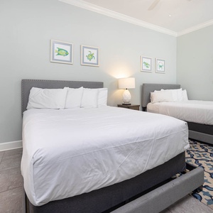 Inviting guest bedroom featuring two queen beds, coastal artwork, and a coastal vibe