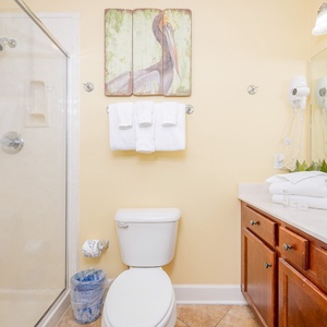 Inviting guest bathroom featuring a walk-in shower, fresh towels, and stylish wooden cabinetry for a relaxing stay