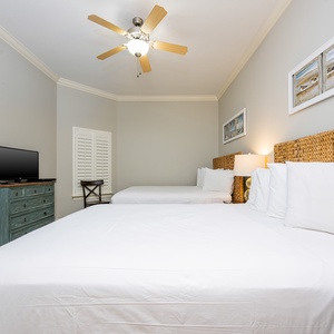 This guest bedroom features two comfortable queen beds, a flat-screen TV, and coastal decor for a relaxing stay