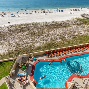 the vibrant pool area features orange lounge chairs, with guests enjoying the water and a view of the beach beyond