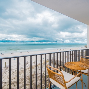 Enjoy a relaxing view of the beach from this cozy balcony with a round table and two chairs, perfect for morning coffee
