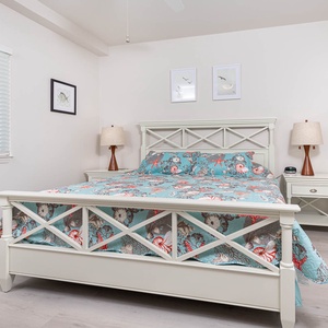 This bedroom features a charming light blue and coral quilt, a cozy bedside lamp, and a serene atmosphere for restful nights