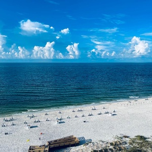 Pause to admire endless blue gulf waters meeting the horizon and rows of chairs on the shore