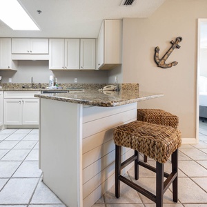 Modern kitchen features granite countertops, a breakfast bar with seating, and stainless appliances