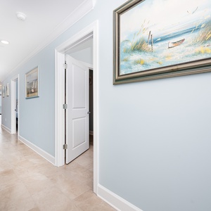 Step into the inviting hallway adorned with coastal artwork, leading you to relaxing spaces and beach views
