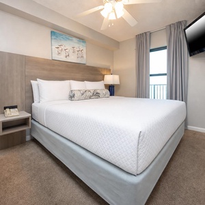 Discover your favorite beach retreat in this king suite with cozy bedding, wall-mounted TV, and adjoining bathroom