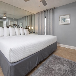 Relax in this cozy bedroom featuring a plush king bed, elegant decor, and a mirrored accent wall for added charm