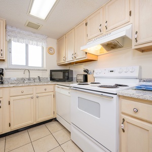 This kitchen features light cabinetry, essential appliances, and a cozy atmosphere perfect for meal preparation