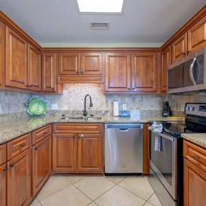 The modern kitchen features rich wood cabinetry, granite countertops, and a convenient breakfast bar with seating