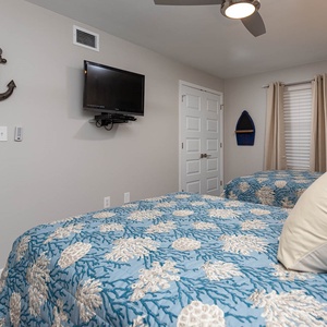 Relax in this inviting guest bedroom featuring two double beds and a wall-mounted TV