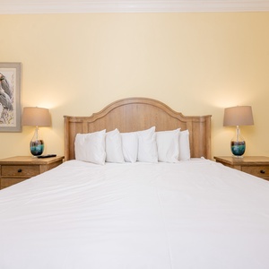 Relax in this inviting guest bedroom featuring a king bed, warm yellow walls, and charming coastal decor