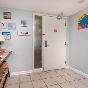 This welcoming entryway features charming coastal artwork, a stylish mirror, and a convenient table for your belongings